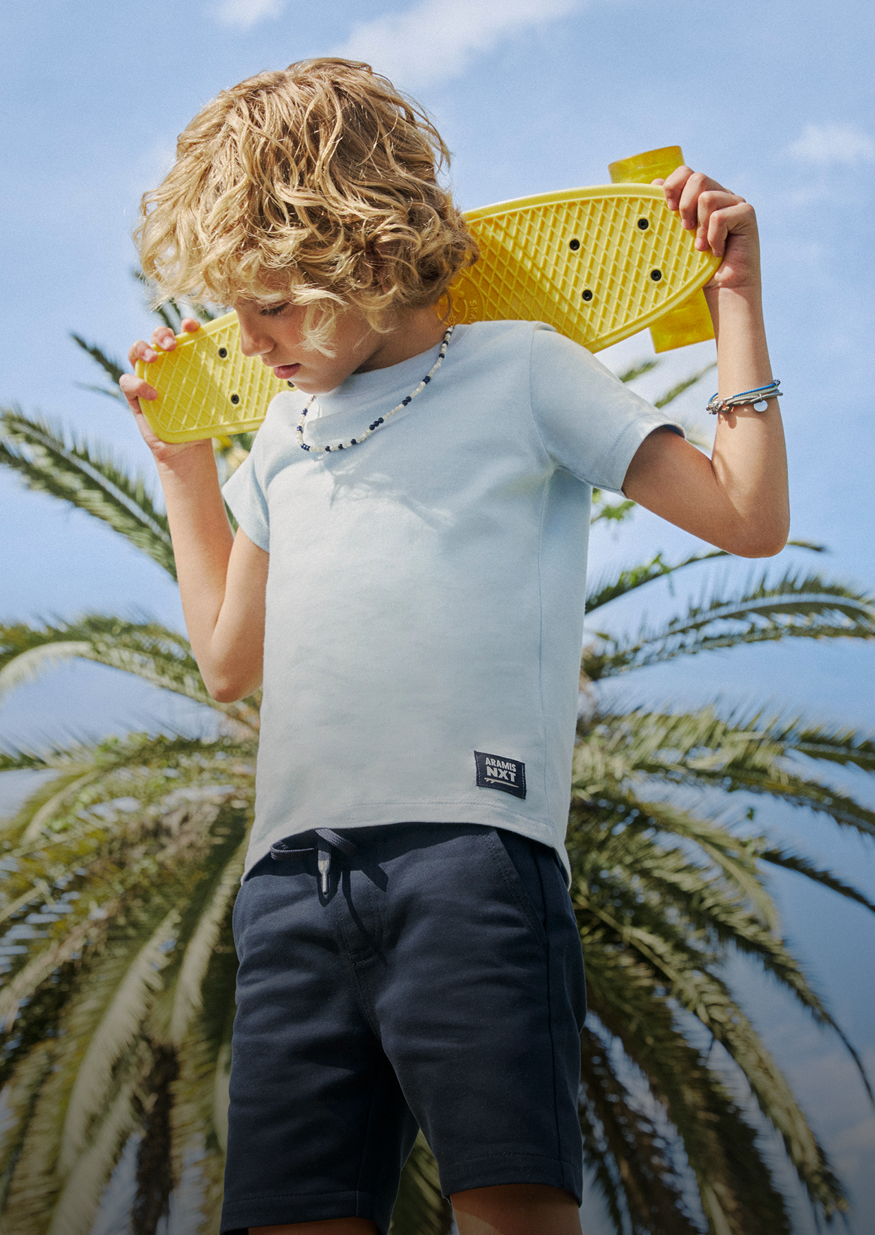 Menino com camiseta azul segurando skate amarelo