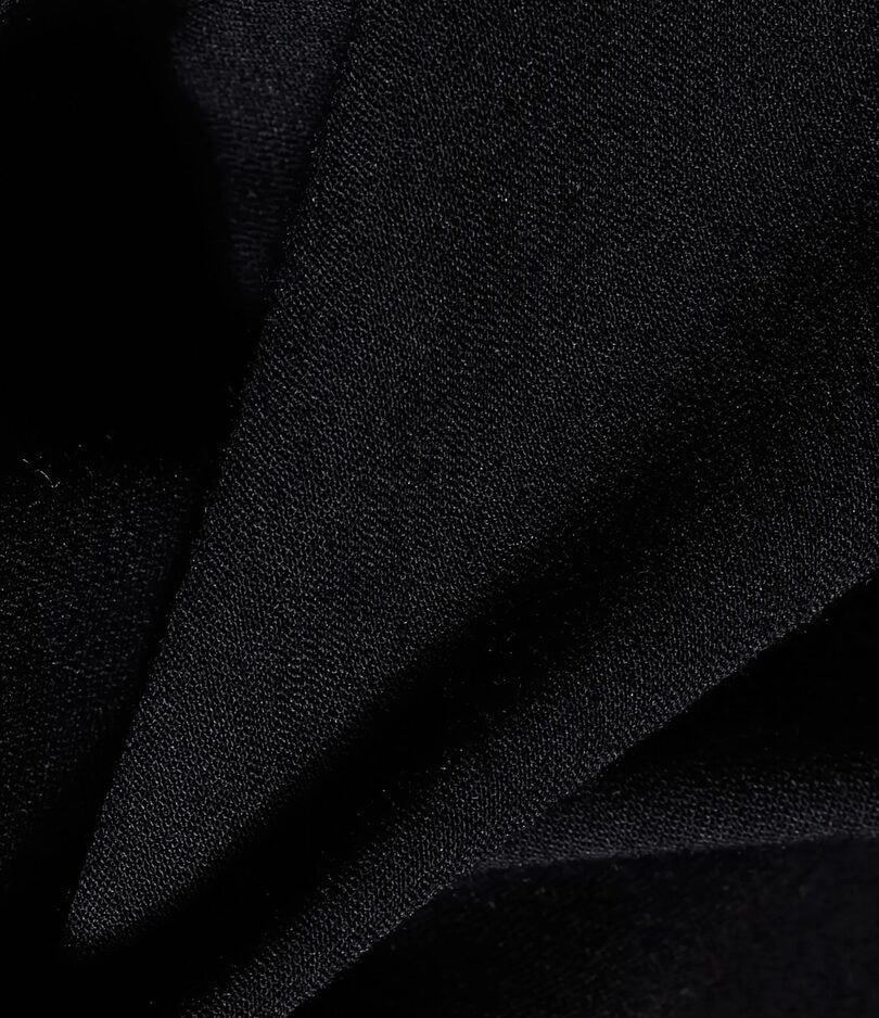 Detalhe aproximado do tecido preto de uma camisa, com a trama e o caimento em close